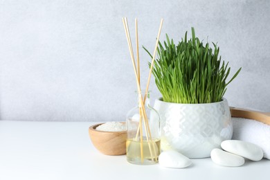 Photo of Spa composition with wheatgrass on white table. Space for text