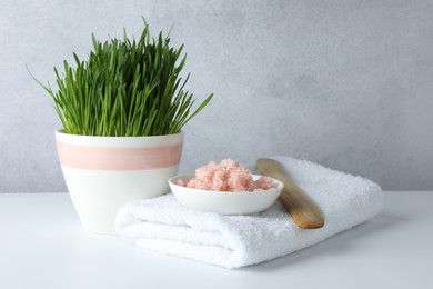 Photo of Spa composition with wheatgrass and sea salt on white table. Space for text