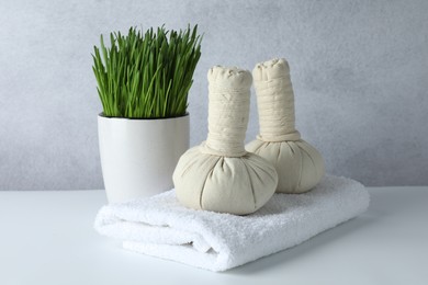 Photo of Spa composition with wheatgrass and herbal bags on white table