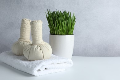 Photo of Spa composition with wheatgrass and herbal bags on white table. Space for text