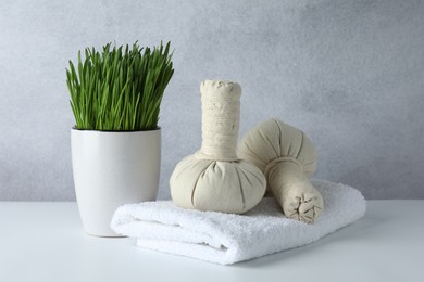 Photo of Spa composition with wheatgrass and herbal bags on white table