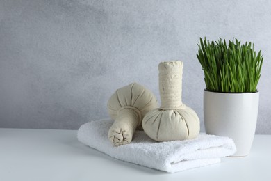 Photo of Spa composition with wheatgrass and herbal bags on white table. Space for text