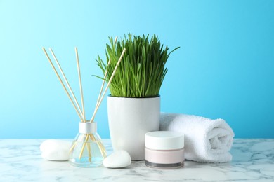 Photo of Spa composition with wheatgrass on white marble table against light blue background