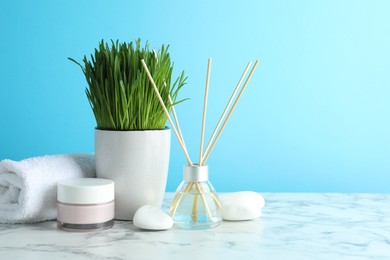 Photo of Spa composition with wheatgrass on white marble table against light blue background. Space for text