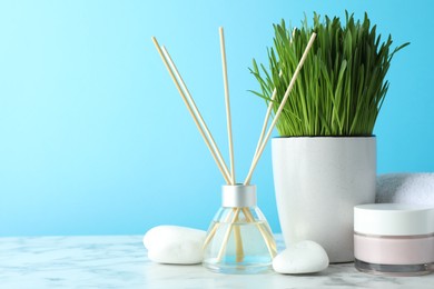 Photo of Spa composition with wheatgrass on white marble table against light blue background. Space for text