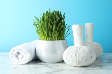 Photo of Spa composition with wheatgrass on white marble table against light blue background