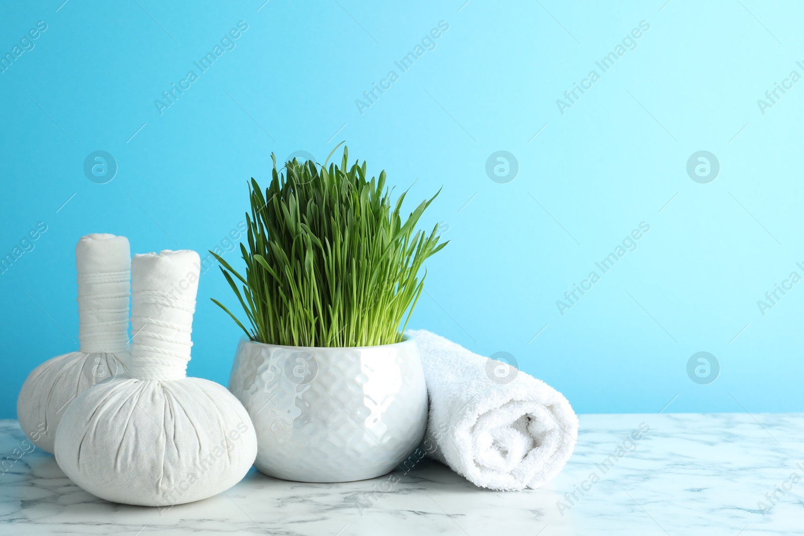 Photo of Spa composition with wheatgrass on white marble table against light blue background. Space for text