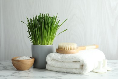 Photo of Spa composition with wheatgrass on white marble table. Space for text