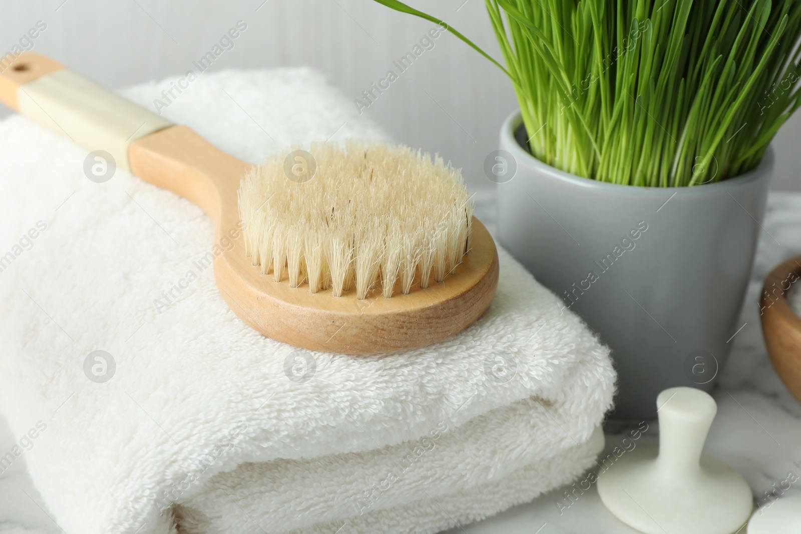 Photo of Spa composition with towel and brush on white marble table, closeup