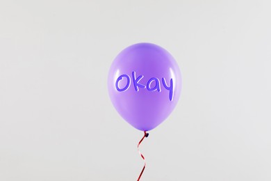 Violet balloon with word Okay on light grey background