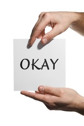 Image of Man holding sheet of paper with word Okay on white background, closeup