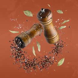 Image of Salt and pepper mills in air on dark orange background