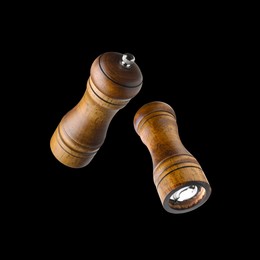 Image of Salt and pepper mills in air on black background