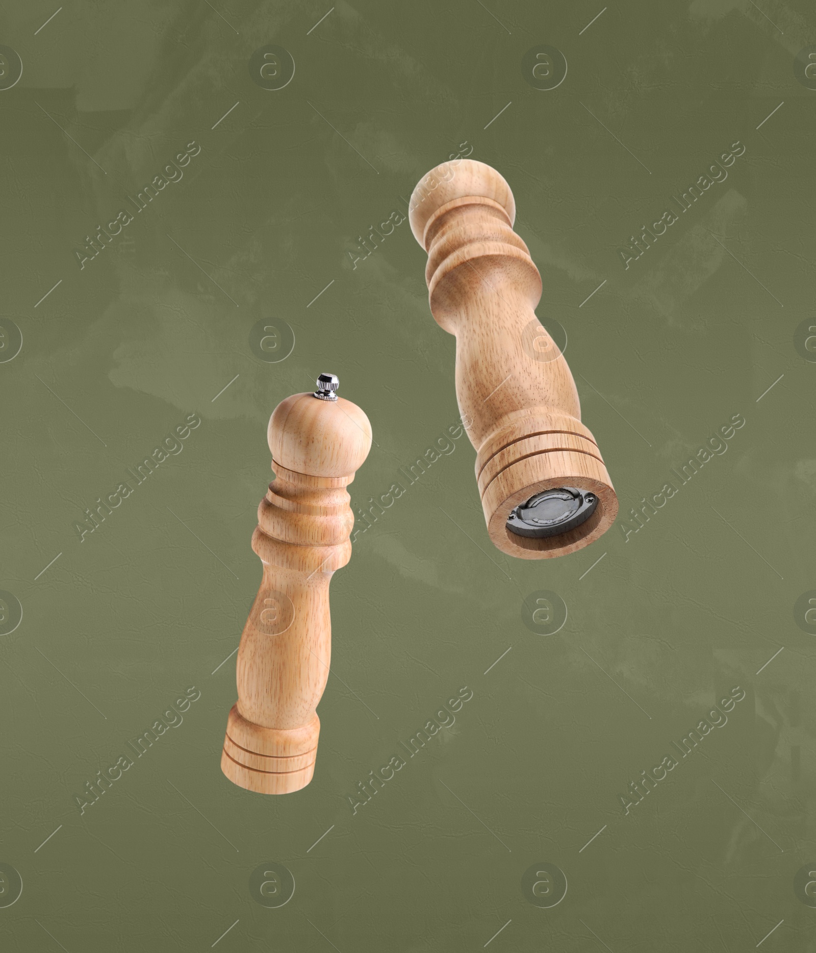 Image of Salt and pepper mills in air on olive color background