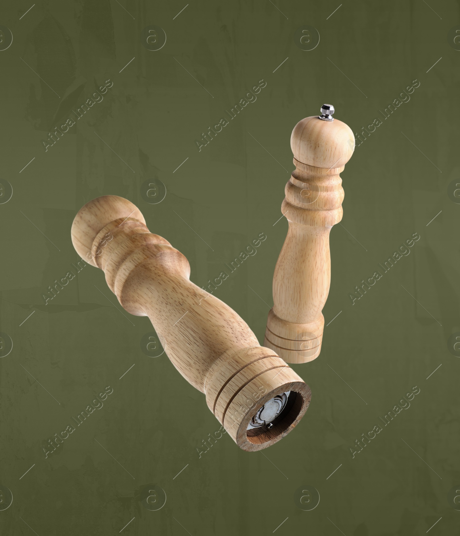 Image of Salt and pepper mills in air on olive color background