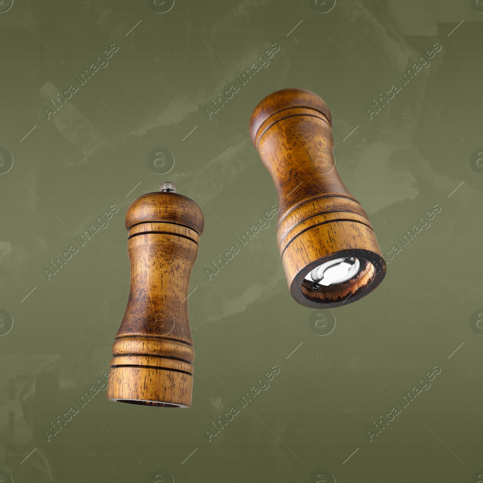 Image of Salt and pepper mills in air on olive color background