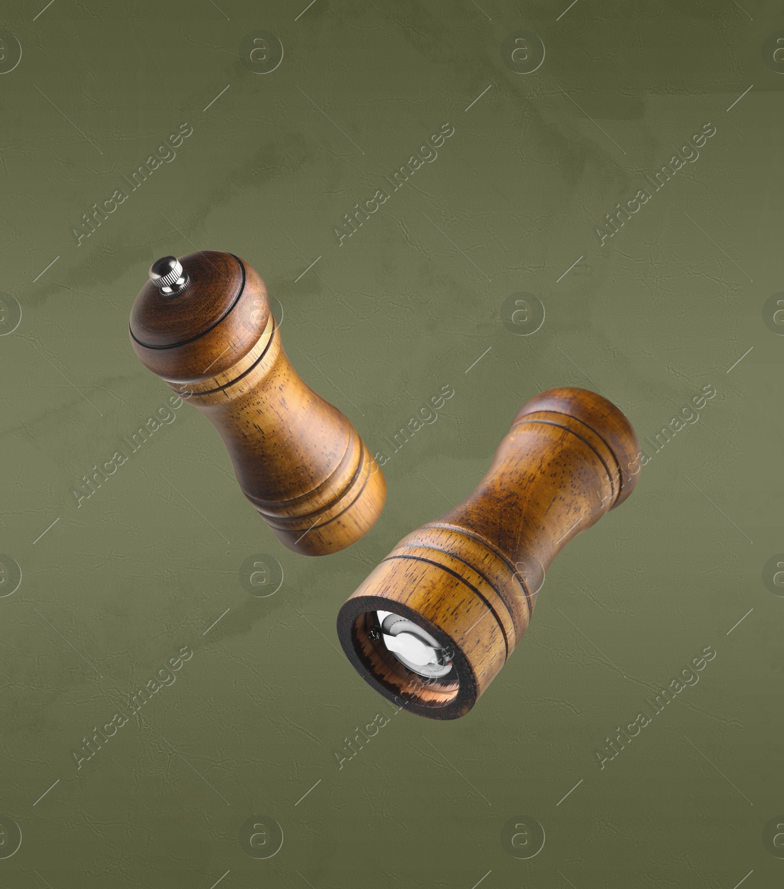 Image of Salt and pepper mills in air on olive color background