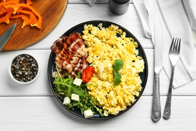 Photo of Tasty brunch. Delicious scrambled eggs, bacon and salad served on white wooden table, flat lay