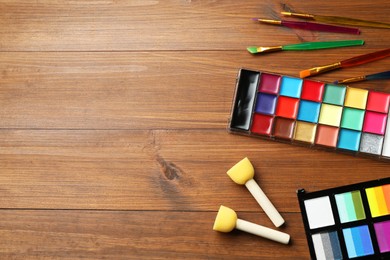 Photo of Face paints and tools on wooden background, flat lay. Space for text