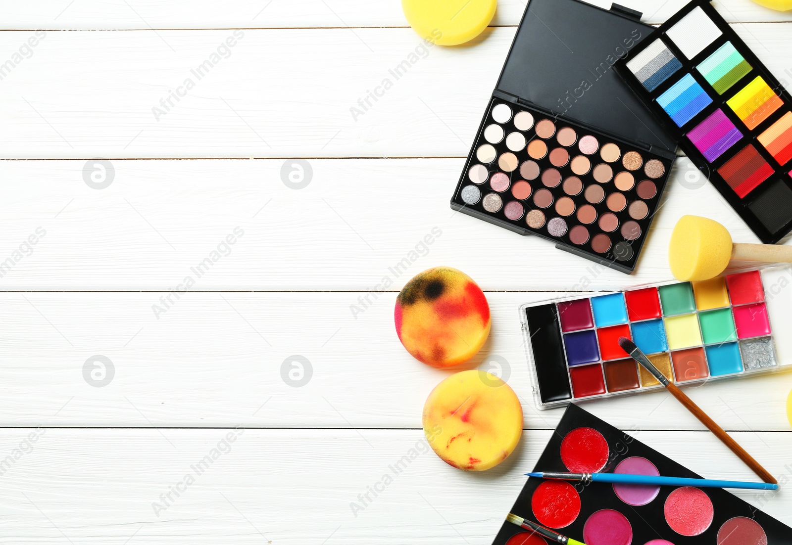 Photo of Face paints, tools and makeup products on white wooden background, flat lay. Space for text