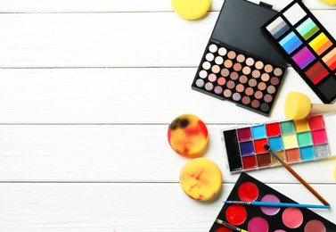 Photo of Face paints, tools and makeup products on white wooden background, flat lay. Space for text