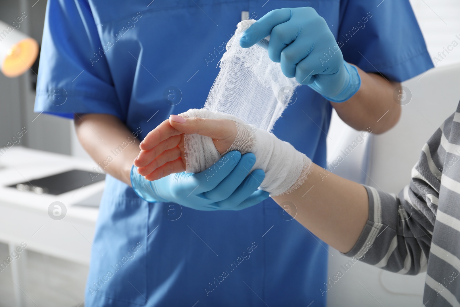 Photo of Doctor bandaging patient's hand in clinic, closeup