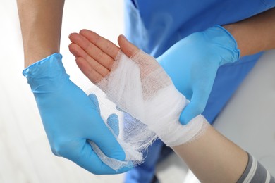 Doctor bandaging patient's hand in clinic, closeup