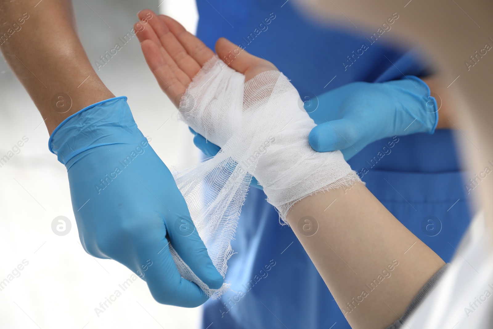 Photo of Doctor bandaging patient's hand in clinic, closeup