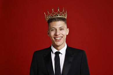 Handsome man wearing luxury crown on red background