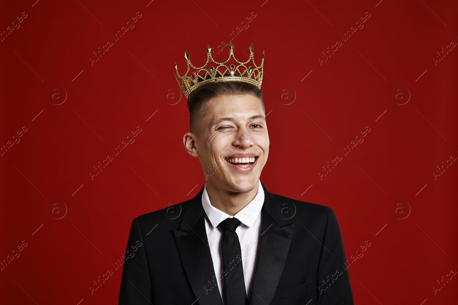 Photo of Handsome man wearing luxury crown on red background