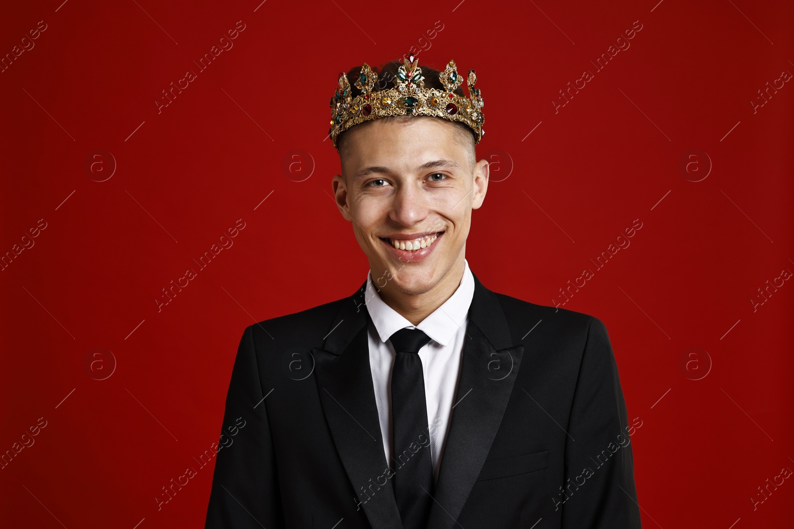 Photo of Handsome man wearing luxury crown on red background