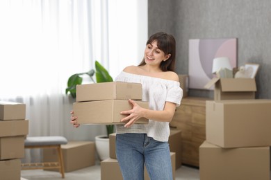 Photo of Moving day. Happy woman with cardboard boxes in her new home