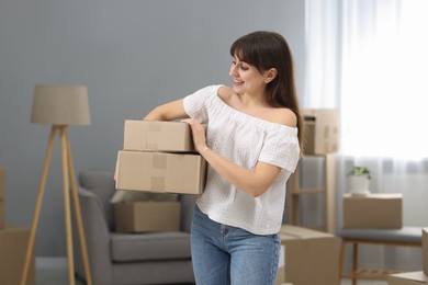 Moving day. Happy woman with cardboard boxes in her new home