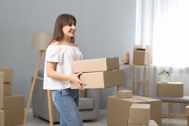 Photo of Moving day. Happy woman with cardboard boxes in her new home