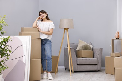 Moving day. Happy woman with her belongings in new home