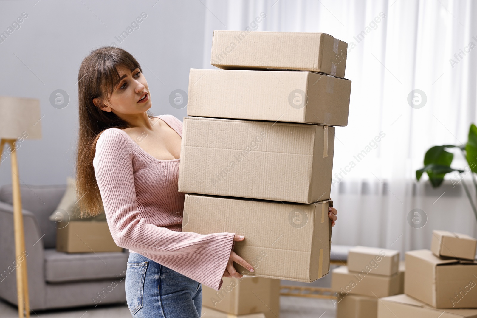 Photo of Moving day. Woman with cardboard boxes in her new home