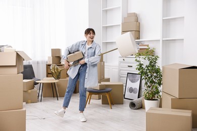 Photo of Moving day. Happy woman with lamp and cardboard box in her new home