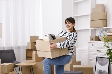 Photo of Moving day. Happy woman with her belongings in new home