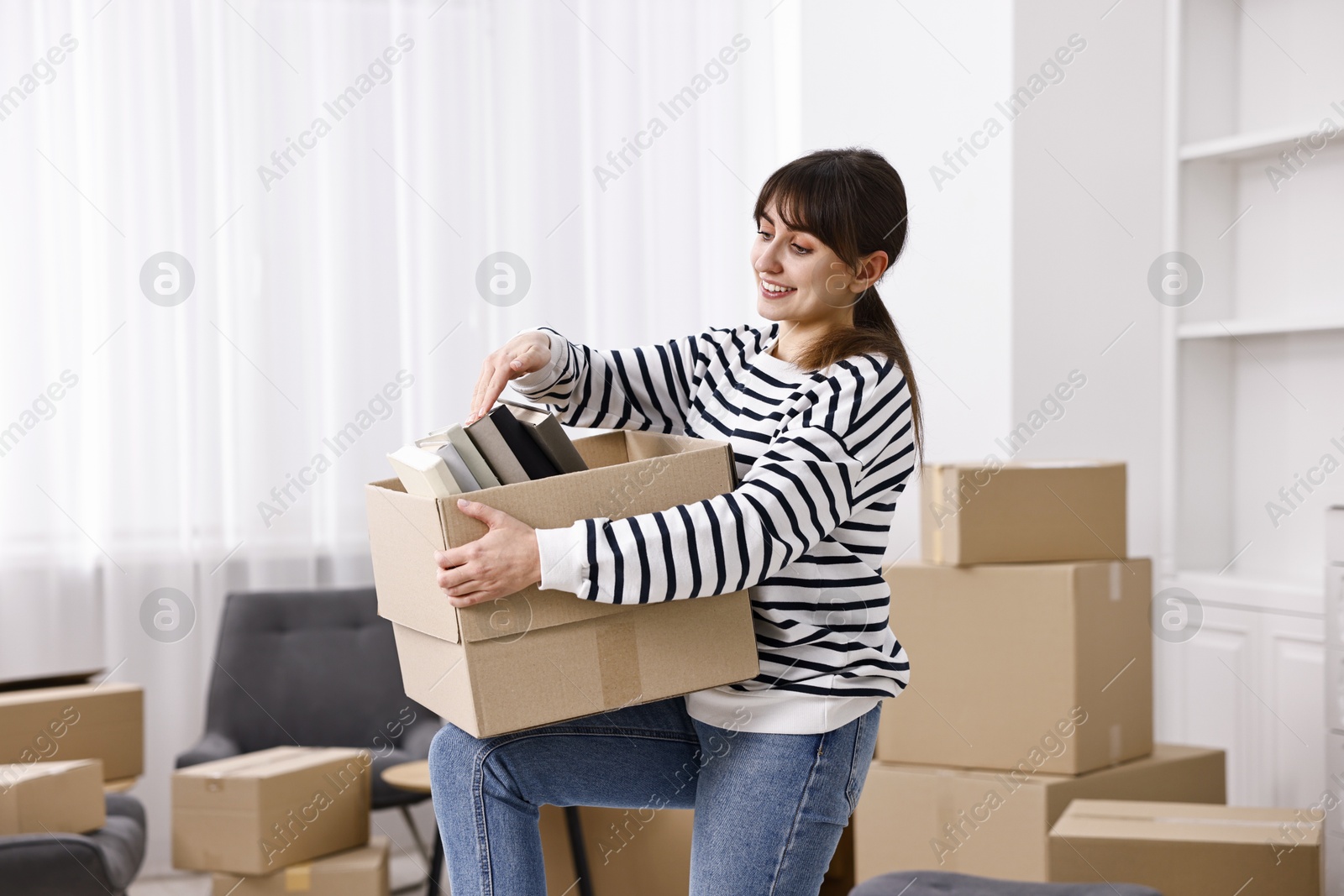 Photo of Moving day. Happy woman with her belongings in new home