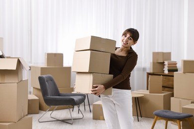 Photo of Moving day. Happy woman with cardboard boxes in her new home