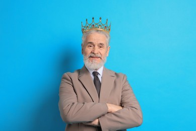 Senior man wearing luxury crown on light blue background