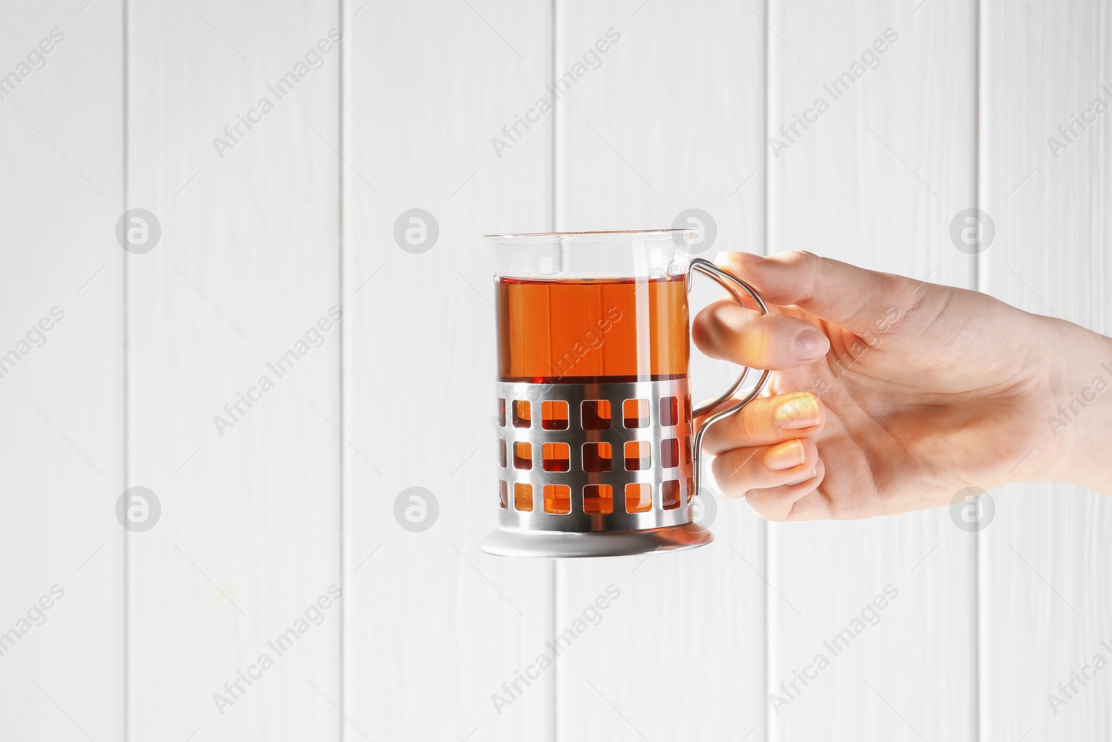 Photo of Woman with glass of tea in metal holder on white wooden background, closeup. Space for text