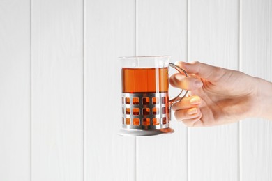 Photo of Woman with glass of tea in metal holder on white wooden background, closeup. Space for text