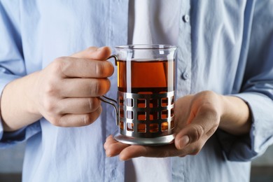 Photo of Woman with glass of tea in metal holder, closeup