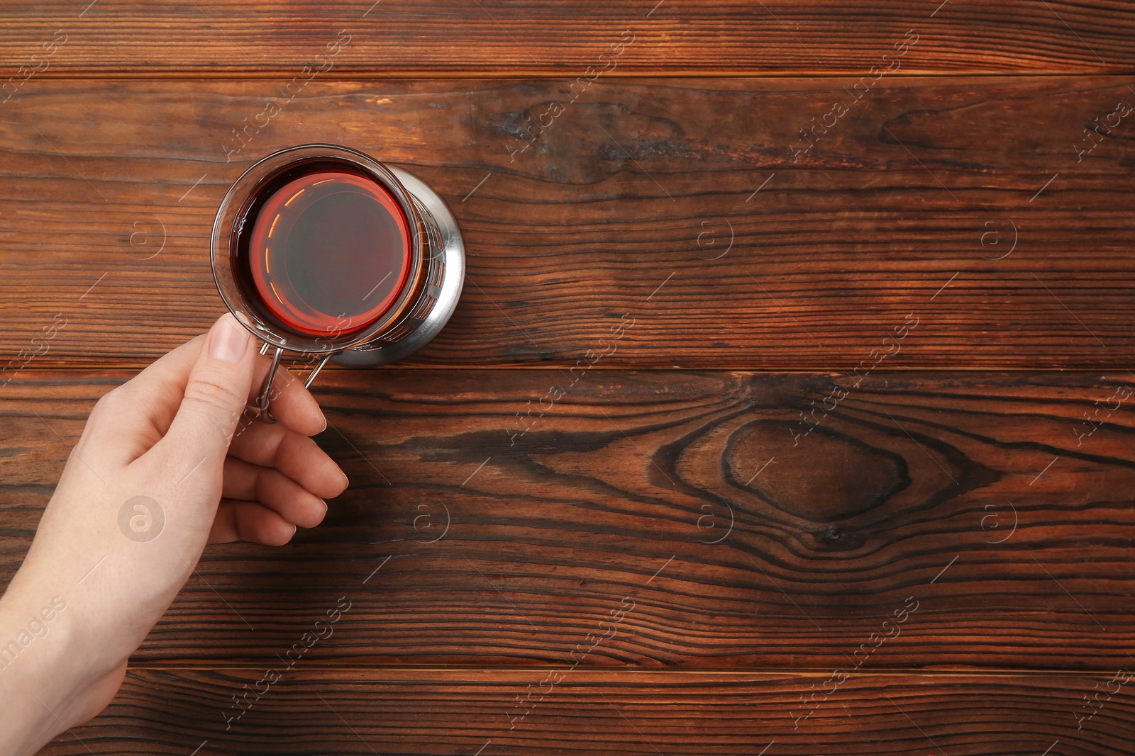 Photo of Woman with glass of tea in metal holder at wooden table, top view. Space for text