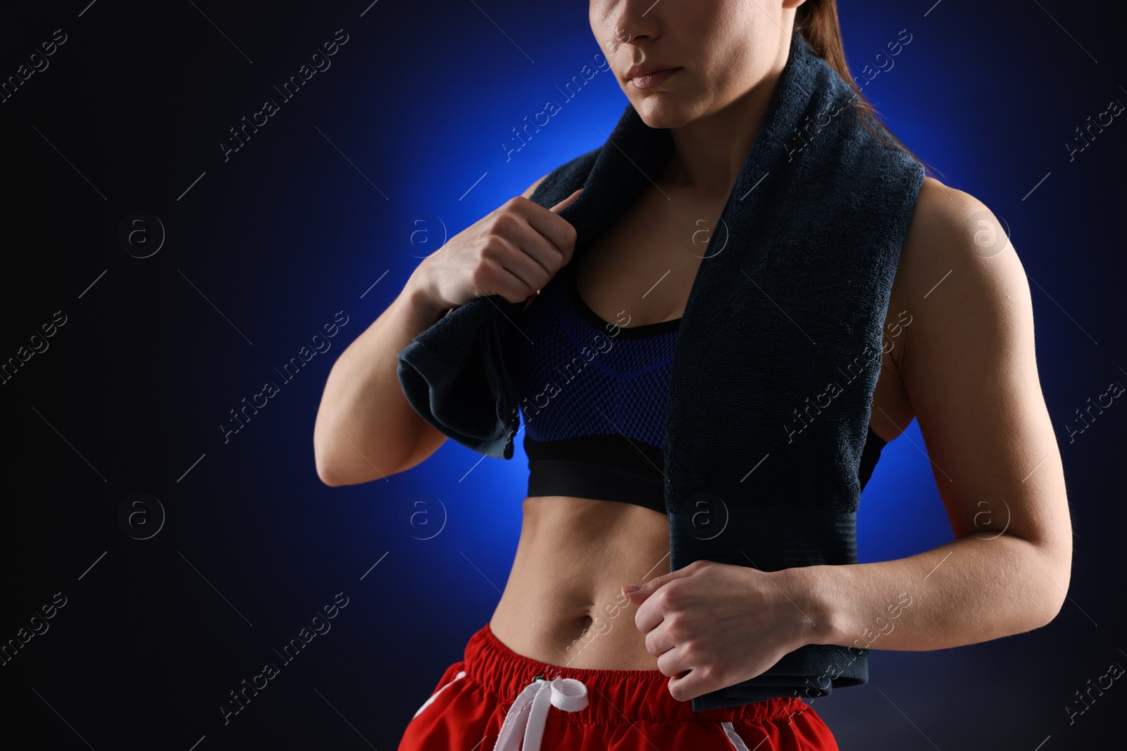 Photo of Sporty woman with terry towel on dark blue background, closeup. Space for text