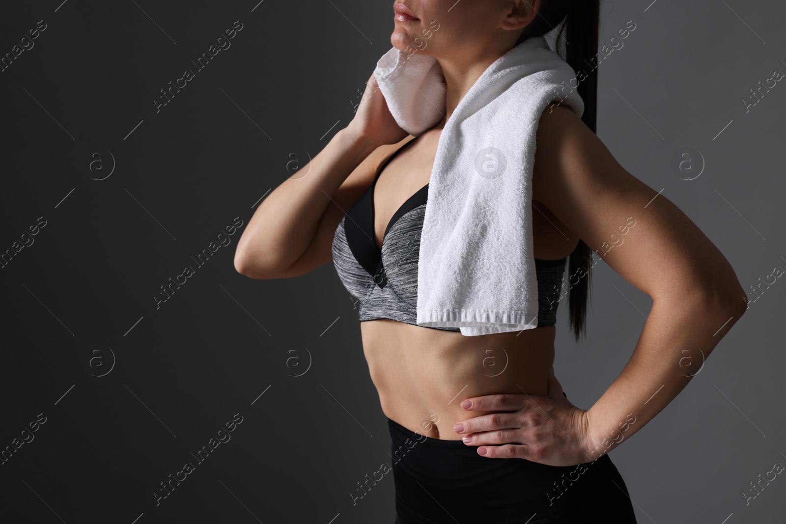 Photo of Sporty woman with terry towel on dark grey background, closeup. Space for text