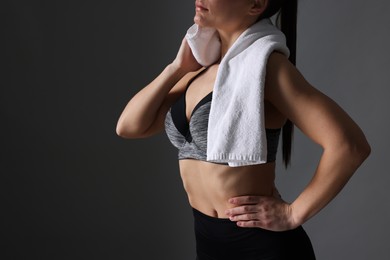 Sporty woman with terry towel on dark grey background, closeup. Space for text