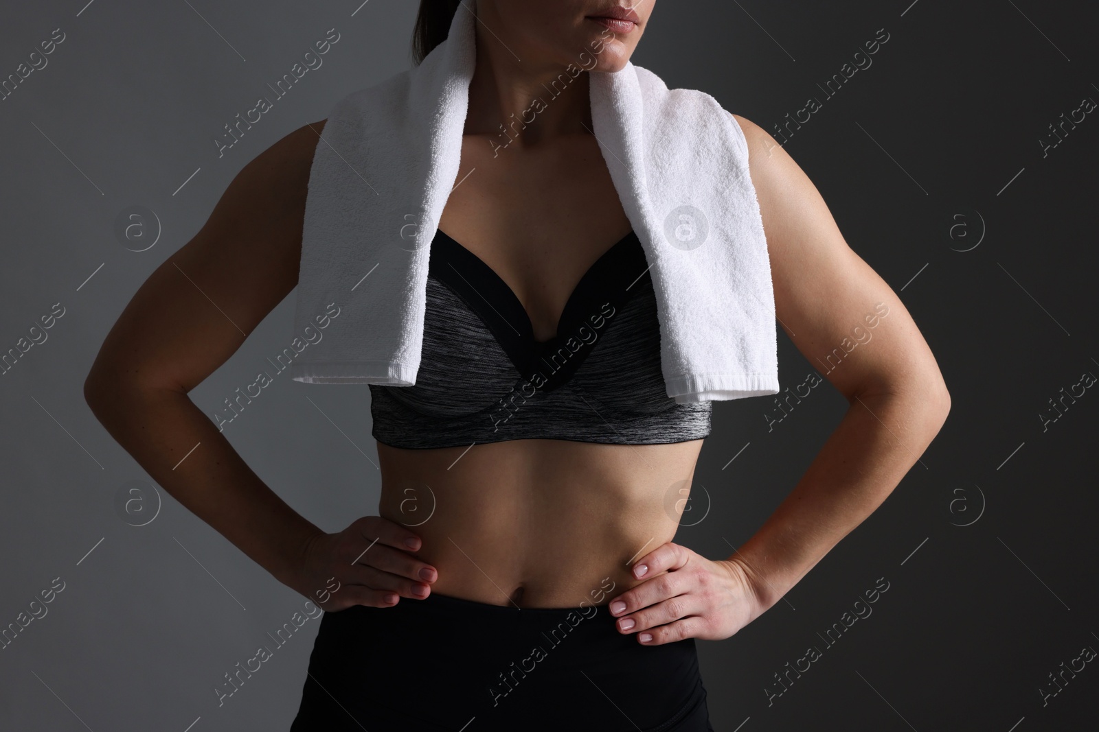 Photo of Sporty woman with terry towel on dark grey background, closeup