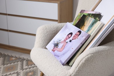 Canvas with different printed photos on armchair indoors, closeup